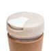A reusable coffee cup with a cork band and a light-colored lid featuring a sliding opening. A reusable coffee cup with a cork band and a light-colored lid featuring a sliding opening.