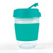 A reusable coffee cup featuring a clear body and a vibrant teal flip lid with a silicone grip band. A reusable coffee cup featuring a clear body and a vibrant teal flip lid with a silicone grip band.