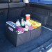A black storage organizer filled with drinks and snacks, displayed in the trunk of a vehicle. A black storage organizer filled with drinks and snacks, displayed in the trunk of a vehicle.