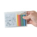 A hand holding a clear case containing coloured pencils in various colors and a drawing pad with a printed image. A hand holding a clear case containing coloured pencils in various colors and a drawing pad with a printed image.