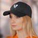A dark grey cap with a curved brim and a logo on the front, modelled by a woman with long blonde hair.