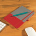 A notebook with a gray cover and a red bottom, paired with a teal pen, on a wooden desk. A notebook with a gray cover and a red bottom, paired with a teal pen, on a wooden desk.