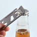 A silver multi-tool is positioned over a bottle cap, ready to open a beverage.