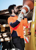 A long sleeve polo in high visibility orange and navy, featuring a logo, worn by a person handling safety equipment. A long sleeve polo in high visibility orange and navy, featuring a logo, worn by a person handling safety equipment.