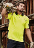 A man in a bright yellow short sleeve polo with black accents, carrying scaffolding pipes at a construction site. A man in a bright yellow short sleeve polo with black accents, carrying scaffolding pipes at a construction site.