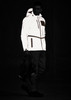A reflective waterproof jacket in white, featuring a hood, zip pockets, and a logo, displayed on a model in a dark setting. A reflective waterproof jacket in white, featuring a hood, zip pockets, and a logo, displayed on a model in a dark setting.