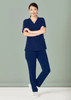 Navy blue women's scrub top and slim leg pant set, featuring pockets and a branding logo. Model is smiling. Navy blue women's scrub top and slim leg pant set, featuring pockets and a branding logo. Model is smiling.