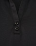 A black polo shirt featuring a textured fabric and two buttons at the neckline. It has a logo on it.