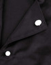 A close-up of a black chef jacket featuring two white exchangeable buttons on the collar.
