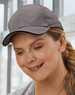 A grey cap with a curved brim, featuring a logo, worn by a woman indoors.