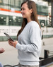 A grey crew fleece jumper, featuring a relaxed fit and long sleeves, is worn by a woman holding a tablet.
