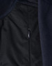 A close-up of a navy blue softshell jacket, featuring a zippered pocket and textured fabric.