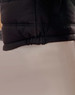 A black heavy quilted puffer jacket featuring a cinched hem and a smooth fabric texture. It has a logo visible.