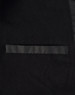 A close-up of a black long line stadium jacket featuring a sleek design and a pocket. The jacket has a branding logo.
