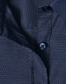A navy blue ladies' button-up shirt with a pin dot pattern and a blue button. Features a classic collar design.