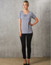 A grey short-sleeve knit top with pleats, paired with black fitted pants, worn by a model against a textured background.