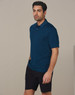 A man wearing a dark teal polo shirt and black cargo shorts, standing against a plain background.