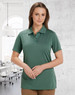 A green ladies' polo shirt featuring a collar and buttons, displayed in a bright office environment.