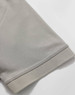 A close-up of a light grey polo shirt sleeve, featuring a solid hem and a smooth fabric texture.