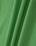 A close-up of a green, textured fabric featuring folds, suitable for polo shirts. It has a branding logo.