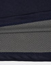A close-up of a navy and charcoal polo shirt, featuring a textured fabric and a logo.