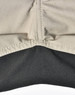 A close-up of Rip-Stop poly/cotton stretch work pants, featuring a beige upper section and a black lower section with stitching.