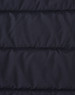 A close-up of a navy blue insulated puffer jacket fabric with a stitched, quilted pattern and a logo.