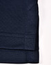 A close-up of a navy blue sustainable poly/cotton polo shirt sleeve with stitching details. It has a logo.