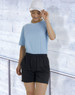 A model wears black bamboo charcoal sports shorts paired with a light blue top and a white cap against a textured background.