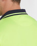 A close-up of the collar of a unisex hi-vis polo shirt in fluorescent yellow with navy detailing.
