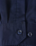 A close-up of a blue long-sleeve shirt featuring segmented tape, with a buttoned cuff detail.