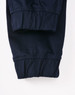 A pair of navy unisex cotton stretch drill cuffed work pants with gathered cuffs. Features a logo on the waistband.