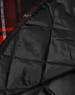 A black quilted flannel shirt with a red and black checkered pattern inside and a logo present.
