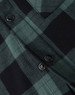 A close-up of a black and green flannel plaid shirt featuring button details. The shirt has a classic check pattern.