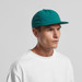A teal cap with a flat brim, featuring a logo, worn by a male model in a white shirt. A teal cap with a flat brim, featuring a logo, worn by a male model in a white shirt.