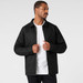 A man wearing a black service jacket, featuring a straight-cut design and a zip closure.