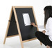 A magnetic black chalkboard A-frame with a wooden frame, being used by a person to attach a note.