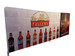 A tension fabric display featuring various beer bottles against a brick wall background, with a prominent logo and branding.