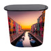 A promotional table featuring a vibrant image of colourful buildings by a canal at sunset, with a black top.