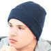A navy blue beanie worn by a model, featuring a ribbed texture and a snug fit. It has a logo on the side.