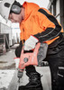 A worker in an orange and black hi-vis pullover hoodie using a power drill while wearing protective gear and gloves. A worker in an orange and black hi-vis pullover hoodie using a power drill while wearing protective gear and gloves.