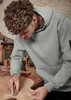 A unisex multi-pocket hoodie in green worn by a person working on wood, featuring a logo on the sleeve.
