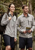 A women's long sleeve button-up shirt in light grey, worn with dark shorts, features a front pocket and branding. A women's long sleeve button-up shirt in light grey, worn with dark shorts, features a front pocket and branding.