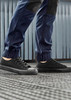 A pair of navy work pants with black accents, worn with black casual shoes on a patterned floor. A pair of navy work pants with black accents, worn with black casual shoes on a patterned floor.