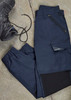 A pair of navy women's work pants laid flat, featuring pockets and an elastic waistband, beside a work boot. A pair of navy women's work pants laid flat, featuring pockets and an elastic waistband, beside a work boot.
