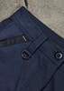 A close-up of navy work pants featuring a belt loop, button closure, and a side black panel. Contains a branded logo. A close-up of navy work pants featuring a belt loop, button closure, and a side black panel. Contains a branded logo.