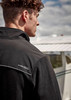 A black unisex quarter-zip polar fleece with a collar and a logo, worn by a model outdoors near an aircraft.
