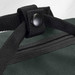 A close-up of a dark green duffle bag showing sturdy black straps and a button fastening. The bag has a textured surface.