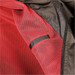 A close-up of a jacket's interior featuring black mesh fabric with red detailing and a zippered closure. A close-up of a jacket's interior featuring black mesh fabric with red detailing and a zippered closure.