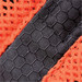 Close-up of a textured fabric featuring a hexagonal pattern, with orange and black elements visible.